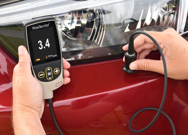 PosiTector 200 B1 ultrasonic coating thickness gauge measuring a plastic bumper
